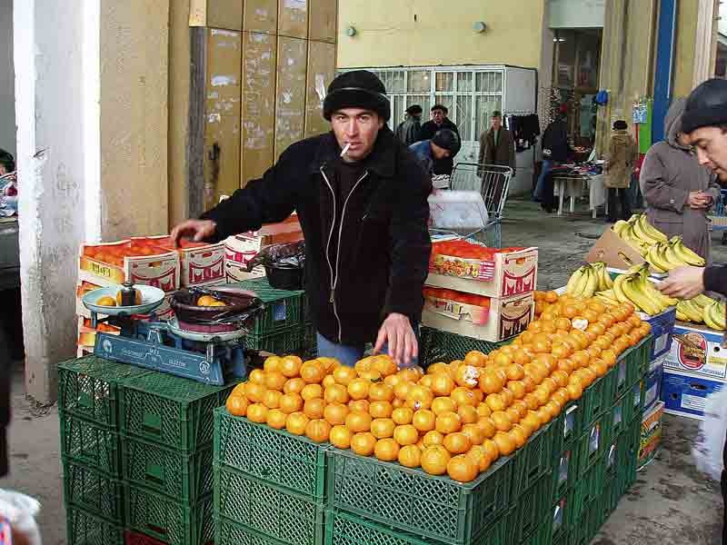 Таджик на рынке. Рынок мандарин. Торговля мандаринами. Продавец мандаринов на рынке. Ящики с мандаринами на базаре.